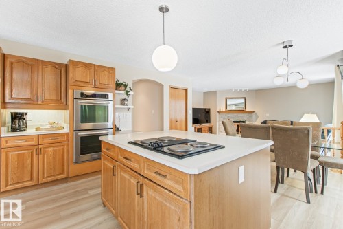 Kitchen with hanging light fixtures, a center island, stainless steel double oven, wood finish cabinetry, and light countertops - 121 Weaver Drive, Edmonton, AB - Indoor Photo Showing Kitchen
