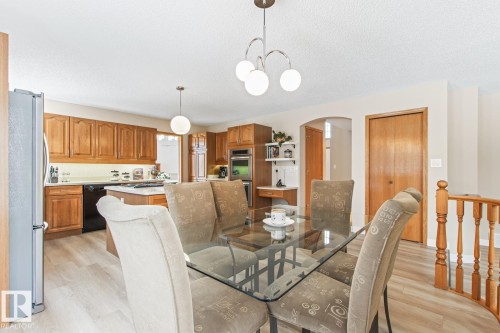 Dining room with arched walkways, light wood-style floors, a textured ceiling, and suspended lighting - 121 Weaver Drive, Edmonton, AB - Indoor Photo Showing Dining Room