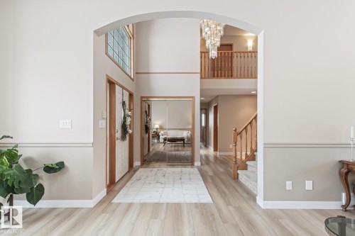Foyer entrance featuring light wood-style floors, a chandelier, a high ceiling, and arched walkways - 121 Weaver Drive, Edmonton, AB - Indoor Photo Showing Other Room