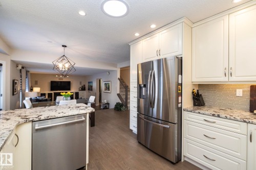 Kitchen featuring light stone countertops, dishwasher, suspended lighting, decorative backsplash, and range - 932 110A Street, Edmonton, AB - Indoor Photo Showing Kitchen With Upgraded Kitchen