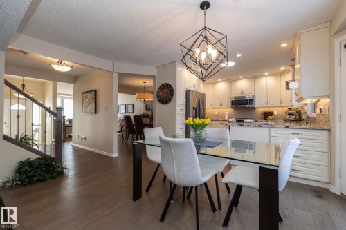 Kitchen with light stone countertops, stainless steel appliances, a textured ceiling, a peninsula, and hanging lights - 932 110A Street, Edmonton, AB - Indoor Photo Showing Dining Room