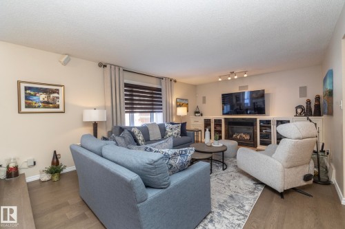Living area featuring a textured ceiling, a glass covered fireplace, and wood finished floors - 932 110A Street, Edmonton, AB - Indoor Photo Showing Living Room With Fireplace