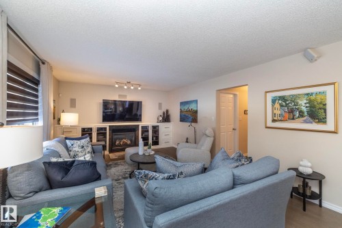 Living area featuring a textured ceiling, a glass covered fireplace, and wood finished floors - 932 110A Street, Edmonton, AB - Indoor Photo Showing Living Room With Fireplace