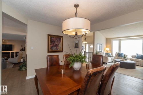Dining area with dark wood-style flooring, a fireplace, and suspended lighting - 932 110A Street, Edmonton, AB - Indoor Photo Showing Dining Room