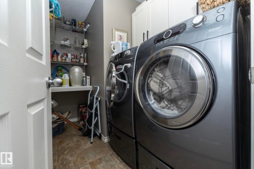 Laundry room with cabinet space, separate washer and dryer, and stone finish floors - 932 110A Street, Edmonton, AB - Indoor Photo Showing Laundry Room