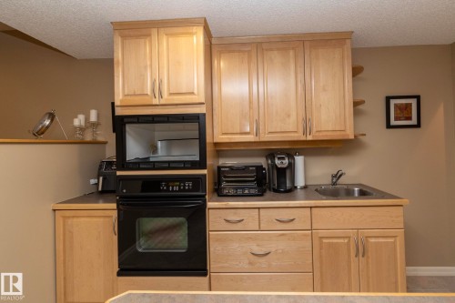 Kitchen featuring open shelves, oven, light wood finish cabinetry, and a textured ceiling - 932 110A Street, Edmonton, AB - Indoor Photo Showing Kitchen