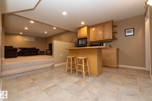 Kitchen with a kitchen bar, open floor plan, light countertops, a textured ceiling, and open shelves - 932 110A Street, Edmonton, AB - Indoor