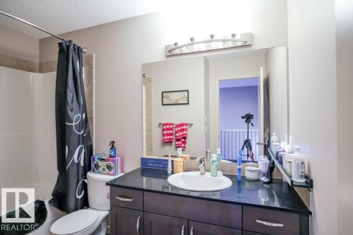 Bathroom with vanity, shower / tub combo with curtain, and a textured ceiling - 1426 25 Avenue Nw, Edmonton, AB - Indoor Photo Showing Bathroom