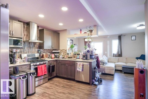 Kitchen featuring a peninsula, open floor plan, stainless steel appliances, light wood-type flooring, and tasteful backsplash - 1426 25 Avenue Nw, Edmonton, AB - Indoor Photo Showing Kitchen