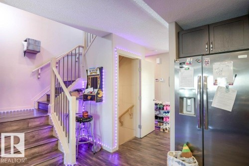Kitchen featuring stainless steel fridge, a textured ceiling, dark wood-style flooring, and dark wood finish cabinetry - 1426 25 Avenue Nw, Edmonton, AB - Indoor Photo Showing Other Room