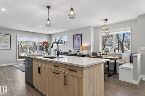 Kitchen with light wood finish cabinets, dark wood-style floors, hanging light fixtures, a kitchen island with sink, and black dishwasher - 9103 120 Avenue, Edmonton, AB - Indoor Photo Showing Kitchen