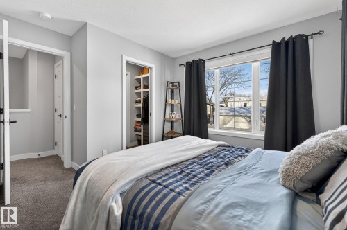 Carpeted bedroom featuring a walk in closet and baseboards - 9103 120 Avenue, Edmonton, AB - Indoor Photo Showing Bedroom