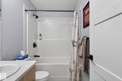 Bathroom with vanity, shower / bath combo with shower curtain, and a textured ceiling - 9103 120 Avenue, Edmonton, AB - Indoor Photo Showing Bathroom