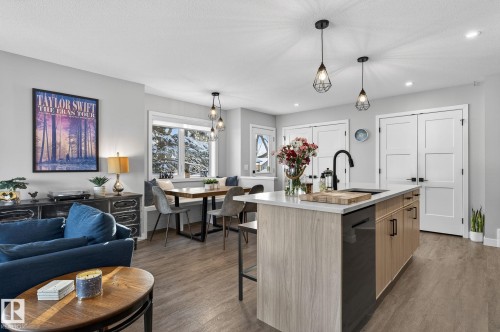 Kitchen with light countertops, a center island with sink, dark wood-style flooring, a kitchen breakfast bar, and dishwashing machine - 9103 120 Avenue, Edmonton, AB - Indoor