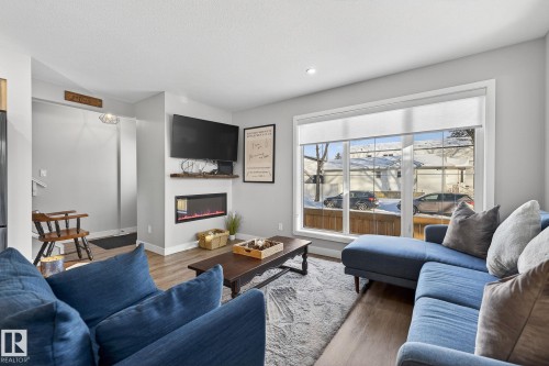 Living area with wood finished floors and a glass covered fireplace - 9103 120 Avenue, Edmonton, AB - Indoor Photo Showing Living Room With Fireplace