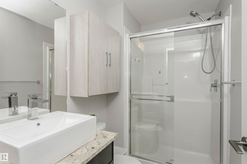 Full bathroom with a shower stall, vanity, and a textured ceiling - 332 5151 Windermere Boulevard, Edmonton, AB - Indoor Photo Showing Bathroom