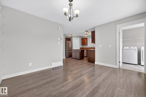Unfurnished living room featuring dark wood-style floors, hanging lights, and a textured ceiling - 2435 Austin Crescent, Edmonton, AB - Indoor Photo Showing Laundry Room