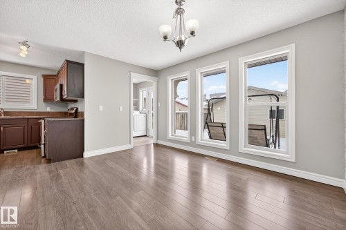 Unfurnished dining area with a textured ceiling, suspended lighting, dark wood-style floors, and washer / dryer - 2435 Austin Crescent, Edmonton, AB - Indoor