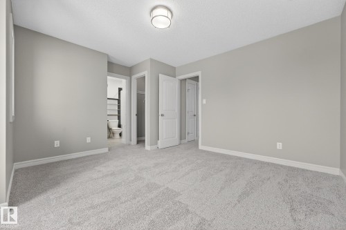 Unfurnished bedroom with carpet, a closet, connected bathroom, and a textured ceiling - 2435 Austin Crescent, Edmonton, AB - Indoor Photo Showing Other Room
