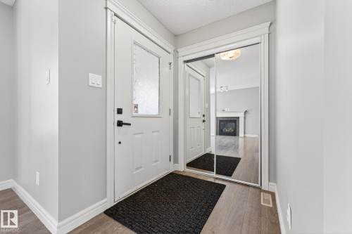 Entrance foyer with wood finished floors, a glass covered fireplace, and a textured ceiling - 2435 Austin Crescent, Edmonton, AB - Indoor Photo Showing Other Room
