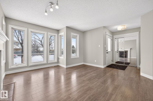 Entryway with wood finished floors, a textured ceiling, and a fireplace - 2435 Austin Crescent, Edmonton, AB - Indoor Photo Showing Other Room