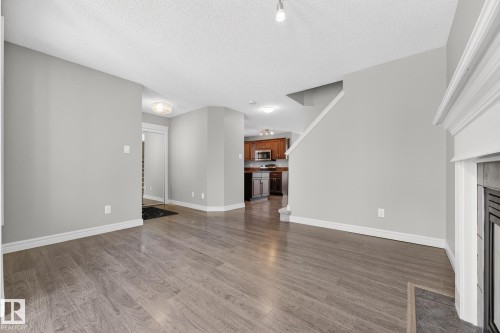 Unfurnished living room featuring wood finished floors, a fireplace with flush hearth, and a textured ceiling - 2435 Austin Crescent, Edmonton, AB - Indoor Photo Showing Other Room With Fireplace