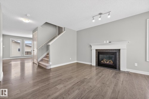 Unfurnished living room with a fireplace, wood finished floors, and a textured ceiling - 2435 Austin Crescent, Edmonton, AB - Indoor Photo Showing Living Room With Fireplace
