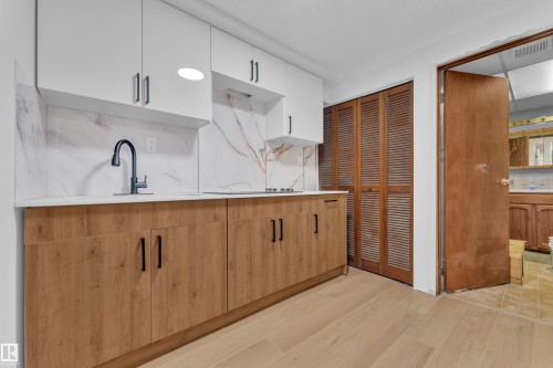 Kitchen featuring modern cabinets, light wood-type flooring, dual tone cabinetry, decorative backsplash, and light stone counters - 5504 18 Avenue, Edmonton, AB - Indoor Photo Showing Kitchen