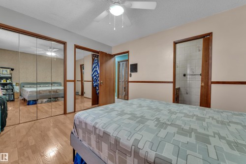 Bedroom with two closets, a textured ceiling, wood finished floors, and ceiling fan - 5504 18 Avenue, Edmonton, AB - Indoor Photo Showing Bedroom