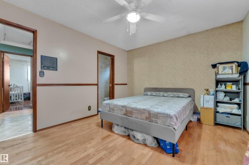 Bedroom with wood finished floors, a textured ceiling, a ceiling fan, wallpapered walls, and connected bathroom - 5504 18 Avenue, Edmonton, AB - Indoor Photo Showing Bedroom