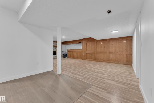 Finished below grade area with light wood-style flooring, wood walls, and a fireplace - 5504 18 Avenue, Edmonton, AB - Indoor Photo Showing Other Room