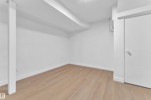 Unfurnished living room with a textured ceiling, light wood-type flooring, and a fireplace - 5504 18 Avenue, Edmonton, AB - Indoor With Fireplace