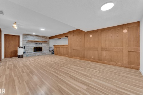 Unfurnished living room with light wood finished floors and a textured ceiling - 5504 18 Avenue, Edmonton, AB - Indoor Photo Showing Other Room