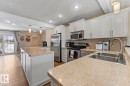 Kitchen featuring hanging light fixtures, white cabinetry, stainless steel appliances, tasteful backsplash, and light countertops - 7 1001 7 Avenue, Cold Lake, AB  - Indoor Photo Showing Kitchen With Double Sink With Upgraded Kitchen 