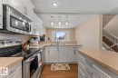 Kitchen with stainless steel appliances, white cabinetry, light countertops, hanging light fixtures, and a textured ceiling - 7 1001 7 Avenue, Cold Lake, AB  - Indoor Photo Showing Kitchen With Double Sink 