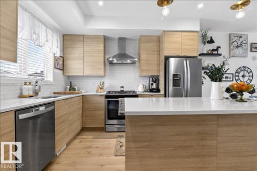 Kitchen featuring light stone counters, stainless steel appliances, light wood-style floors, modern cabinets, and recessed lighting - 6609 47 Avenue, Beaumont, AB - Indoor Photo Showing Kitchen With Upgraded Kitchen