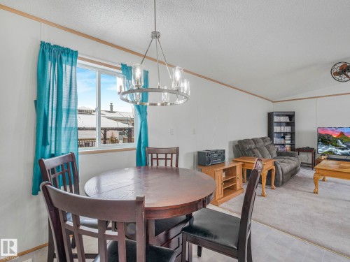 Dining space with ornamental molding, a chandelier, light colored carpet, and light flooring - 151 3400 48 Street, Stony Plain, AB - Indoor Photo Showing Dining Room