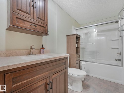 Full bathroom featuring vanity, combined bath / shower with glass door, and a textured ceiling - 151 3400 48 Street, Stony Plain, AB - Indoor Photo Showing Bathroom