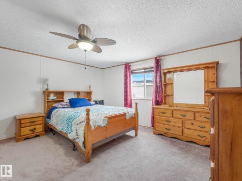 Carpeted bedroom with ornamental molding, ceiling fan, and a textured ceiling - 151 3400 48 Street, Stony Plain, AB - Indoor Photo Showing Bedroom
