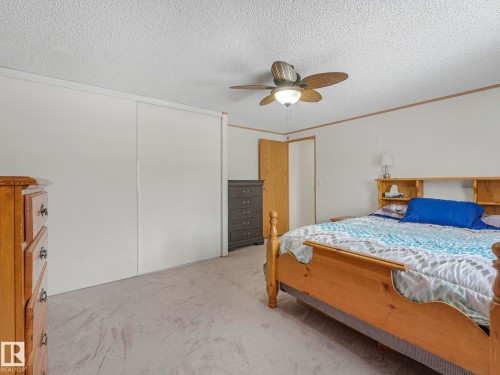 Bedroom with carpet flooring, a ceiling fan, a textured ceiling, crown molding, and a closet - 151 3400 48 Street, Stony Plain, AB - Indoor Photo Showing Bedroom