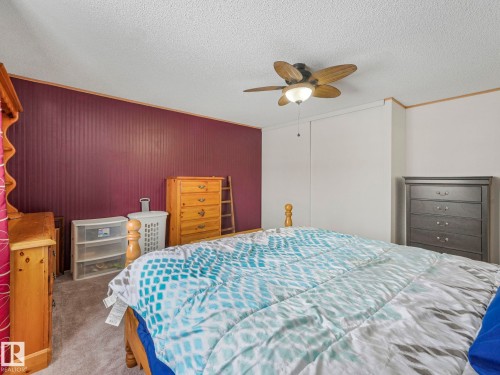 Carpeted bedroom with ornamental molding, a textured ceiling, ceiling fan, and a closet - 151 3400 48 Street, Stony Plain, AB - Indoor Photo Showing Bedroom