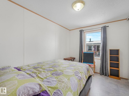 Bedroom featuring crown molding, a textured ceiling, and tile patterned floors - 151 3400 48 Street, Stony Plain, AB - Indoor Photo Showing Bedroom