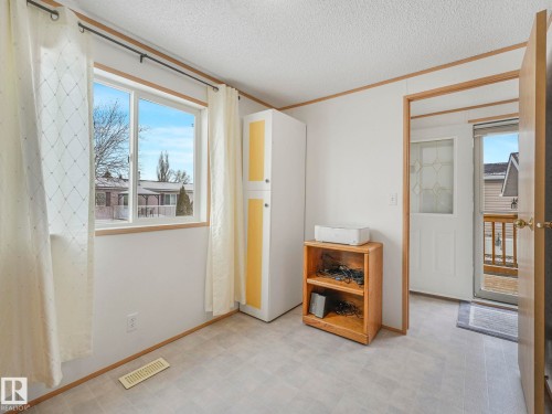 Empty room with light floors, a textured ceiling, healthy amount of natural light, and crown molding - 151 3400 48 Street, Stony Plain, AB - Indoor Photo Showing Other Room