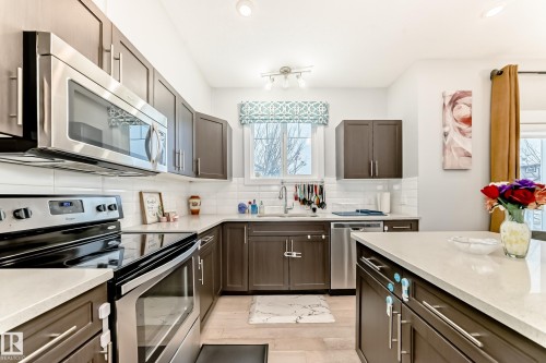 Kitchen with stainless steel appliances, backsplash, light stone counters, dark brown cabinetry, and recessed lighting - 41 4835 Wright Drive, Edmonton, AB - Indoor Photo Showing Kitchen With Stainless Steel Kitchen With Upgraded Kitchen