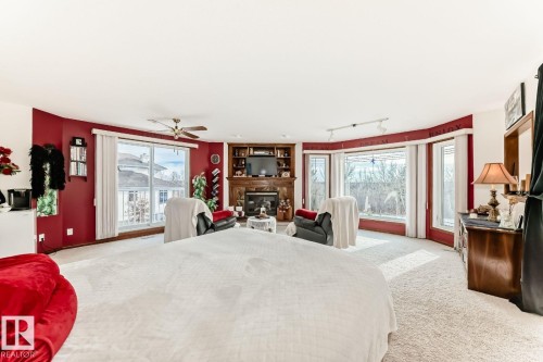 Carpeted bedroom featuring a glass covered fireplace, ceiling fan, and access to outside - 777 Butterworth Drive, Edmonton, AB - Indoor