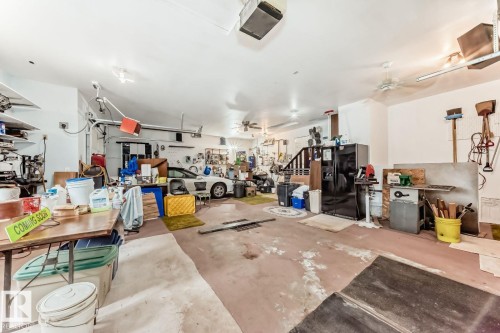 Garage with ceiling fan, black fridge with ice dispenser, and a garage door opener - 777 Butterworth Drive, Edmonton, AB - Indoor Photo Showing Garage