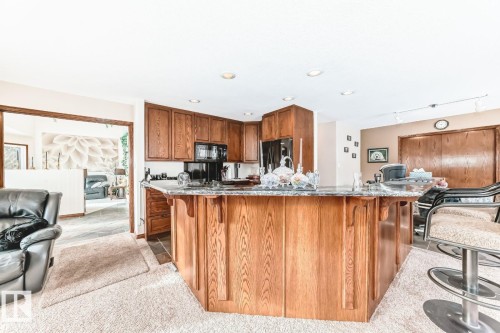 Kitchen featuring a breakfast bar, wood finish cabinets, black appliances, dark stone countertops, and recessed lighting - 777 Butterworth Drive, Edmonton, AB - Indoor Photo Showing Kitchen