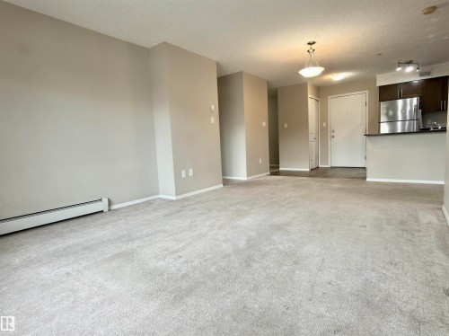 Spacious living area featuring light-colored carpeting and neutral painted walls - 205 11816 22 Avenue, Edmonton, AB - Indoor