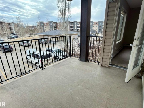 The property features a private balcony with a no maintenance deck covering and a black metal railing - 205 11816 22 Avenue, Edmonton, AB - Outdoor
