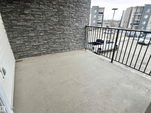 A spacious private balcony with a no maintenance deck covering and black metal railings, offering views of the surrounding area - 205 11816 22 Avenue, Edmonton, AB - Outdoor